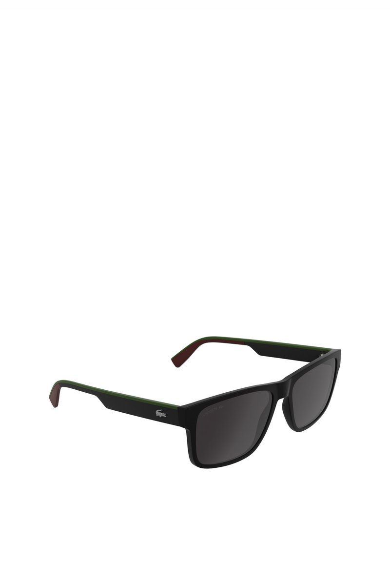 Lunettes de soleil noires de forme rectangulaire, avec des accents verts et brun rougeâtre sur les branches, des verres foncés, et la marque Lacoste.