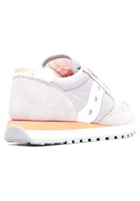 Sneaker in suede grigio e nylon con dettagli bianchi, caratterizzato da una suola texturizzata e una piattaforma arancione chiaro. Vista angolata da dietro.