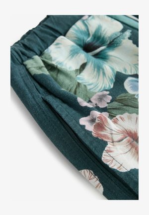 Floral fabric featuring large hibiscus flowers in teal, pink, and green hues, with gathered detailing and a soft texture.