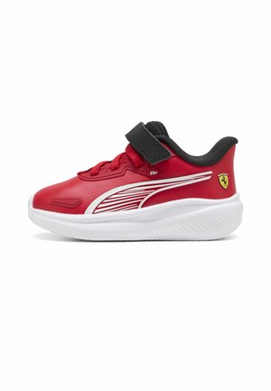 Baskets rouges pour enfant avec semelle blanche, col noir, lacets rouges, bride velcro noire, motif à rayures blanches et logo Ferrari jaune au talon.