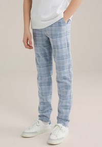 Ljusblå rutig byxor med ett rutmönster, med fickor och en slim fit, matchade med vita sneakers.