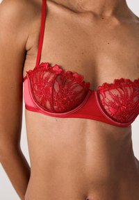 Rode kant en gaas bh met een gestructureerd ontwerp, voorzien van bloemenborduursel en verstelbare bandjes. Glad materiaal aan de zijkanten.