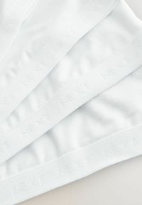 Białe paski materiału z wytłoczonym logo "NEXT" na krawędziach, charakteryzujące się gładką fakturą i równym przeszyciem.