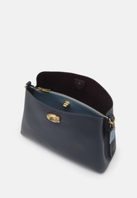 Marinblå läderväska med sträv yta, guldhardware och en kontrasterande ljusblå insida. Utrustad med dragkedjestängning och en platt ficka.