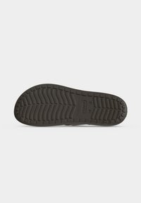 Σόλα καφέ σανδαλιού Crocs που εμφανίζεται επίπεδη με υφή και μοτίβο για καλύτερη πρόσφυση σε λευκό φόντο.