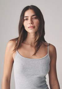 Szary prążkowany top na ramiączkach o dopasowanym kroju i miękkiej fakturze, przedstawiony na neutralnym tle.