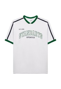 Camiseta blanca con acentos verdes y negros, con cuello en V y el texto "STANDARTS UPDATED" en el pecho junto con "EST.1998."