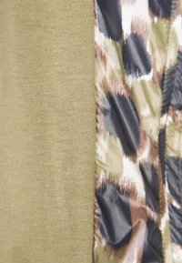 Vihreä neulottu kangas vasemmalla, yhdistettynä teksturoituun, moniväriseen kuviolliseen materiaaliin, jossa tummansinisiä, ruskeita ja valkoisia sävyjä oikealla.