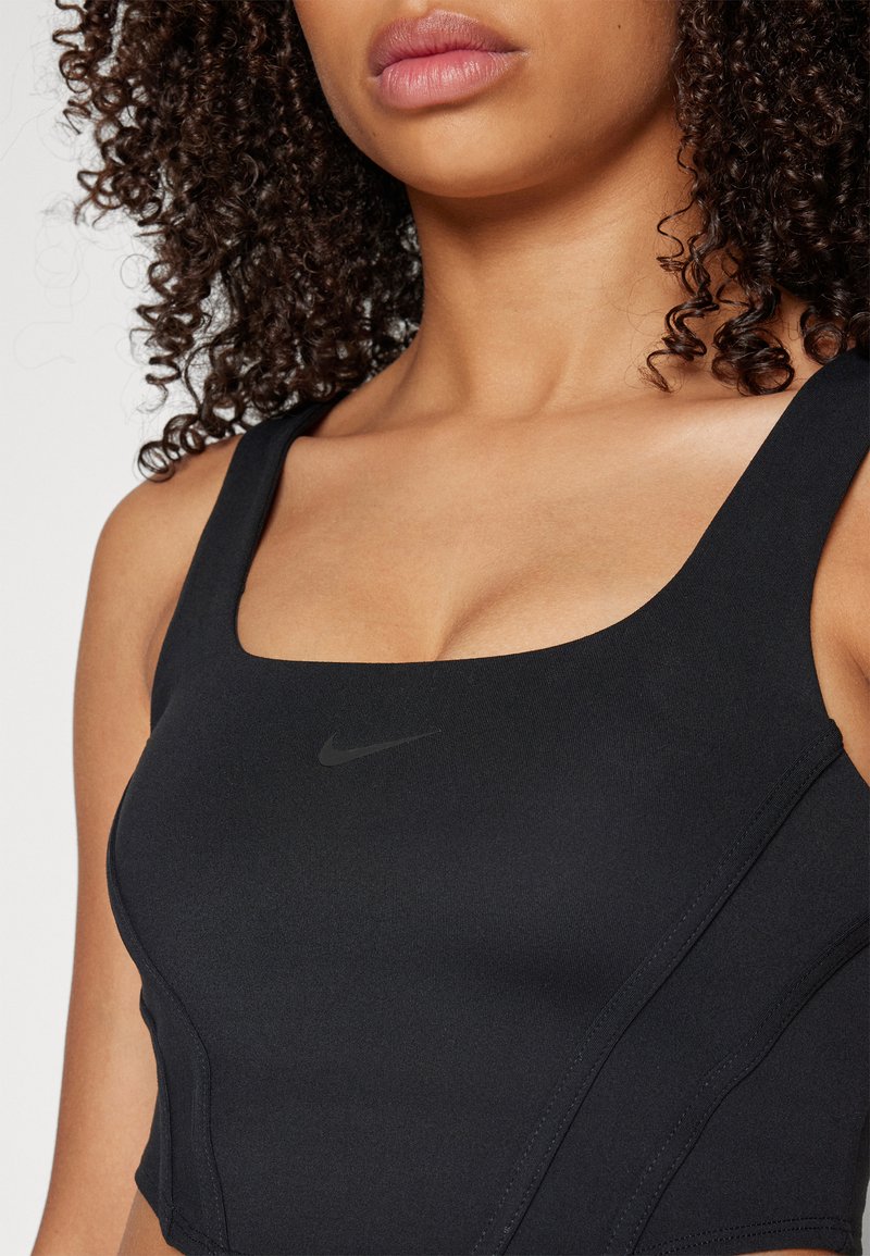 Bra sportivo nero con scollatura quadrata, realizzato in tessuto morbido. Presenta un discreto logo Nike, spalline larghe e costruzione senza cuciture.