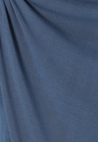 Sininen kangas, jossa on sileä rakenne, esittää hienovaraisen viistokuvion. Materiaali vaikuttaa kevyeltä ja joustavalta.