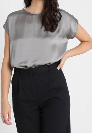 Grå satin kortærmet top med rund hals, parret med højtaljede sorte bukser, der har plisseringer og en skræddersyet pasform.