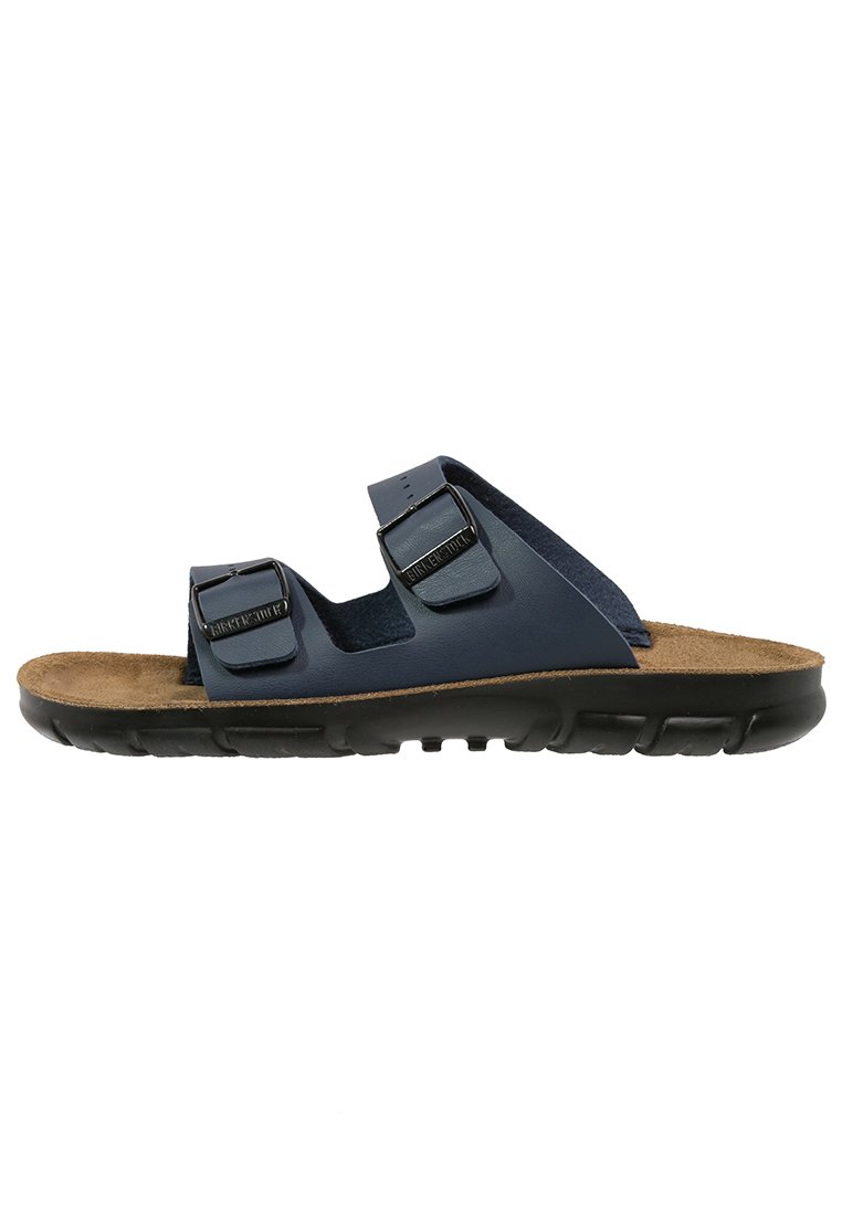 Navy blue slide sandals with two adjustable straps, cork footbed, and a black rubber sole featuring a textured tread pattern.