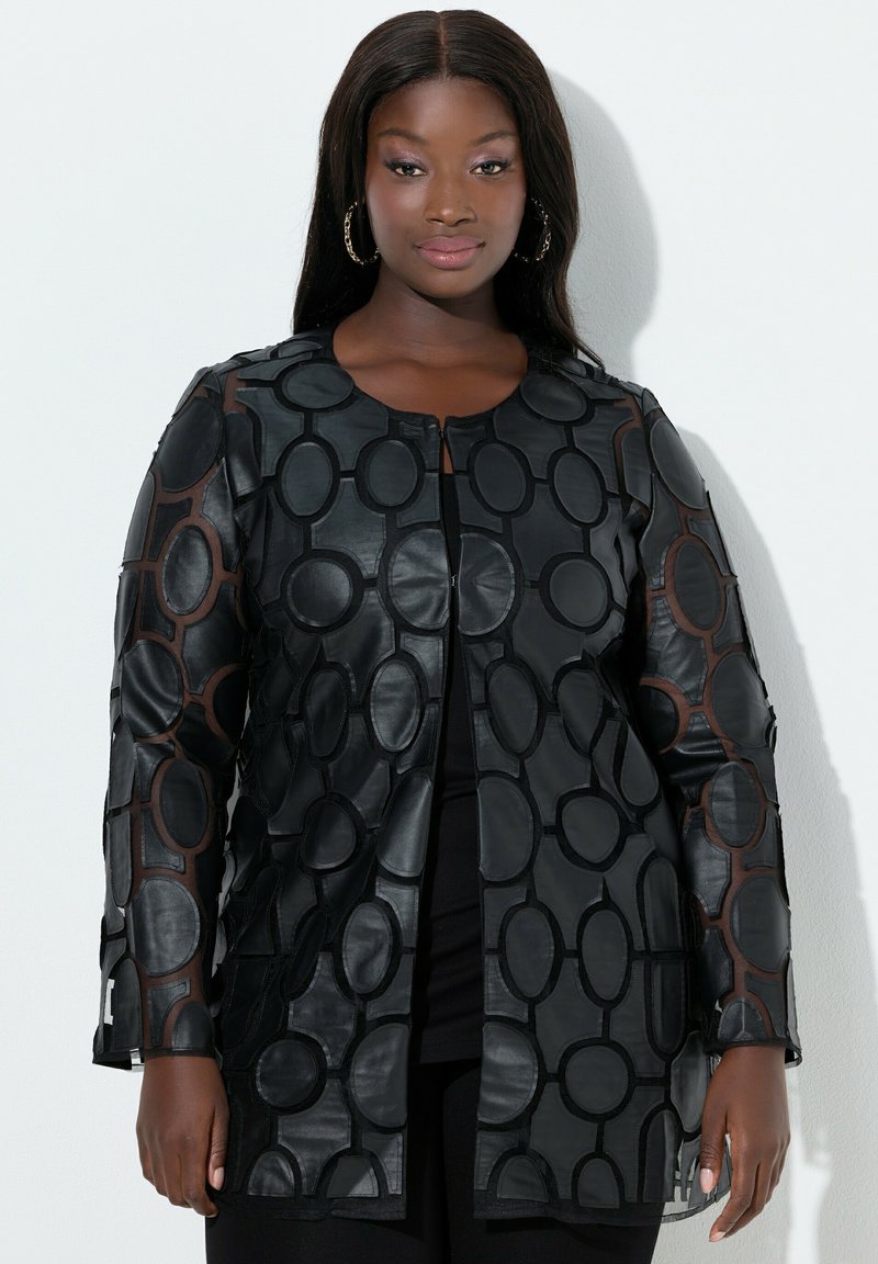 Schwarze Lederjacke mit einem geometrischen Ausschnittdesign, das kreisförmige Muster und lange Ärmel aufweist. Der Stoff hat eine glatte Textur.