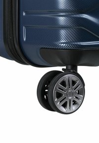 Maleta rígida de color azul oscuro con una superficie texturizada, que cuenta con una sola rueda negra con un diseño plateado para un movimiento suave.
