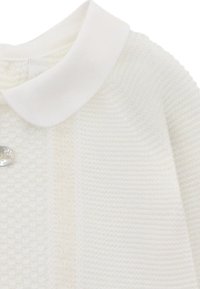 Prenda blanca de punto con un cuello blanco liso y un botón redondo transparente, que muestra un patrón texturizado.