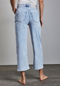 Jasnoniebieskie dżinsowe spodnie 7/8 w luźnym kroju, z tylnymi kieszeniami i lekko wyblakłym kolorem. Posiadają haftowany brzeg i metkę na pasku.