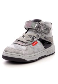 Zapatilla alta plateada de tela texturizada, con acentos brillantes y un panel lateral de charol negro. Presenta una correa de Velcro y cordones.
