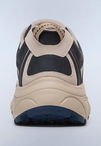 Mustat ja beige lenkkarit, joissa on pehmustettu kaulus, teksturoitu materiaali ja kumipohja. Varustettu logoyksityiskohdalla ja kontrastivärisillä ompeleilla.