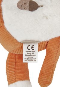 Soft plush toy with a white and orange design, corduroy texture, and embroidered acorn detail. Includes care label on the side.