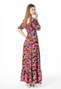 Robe noire à fleurs avec des manches courtes bouffantes, ornée de roses roses et rouges, une taille ajustée et un ourlet à volants. Chaussures à talons transparents.