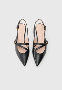 Black leather pointed-toe slingback shoes with cross straps, a buckle accent, and a pink insole, featuring a smooth textured surface.