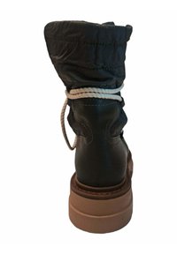 Bota de cuero oscura con un upper textil negro acolchado, costuras tonales, punta redonda y una suela gruesa beige. Incluye un acento de cuerda alrededor del tobillo.