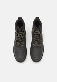 Botas de cuero negras de media caña con acabado texturizado, que presentan cordones de color verde oliva y un cuello acolchado para mayor comodidad y soporte.