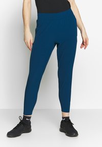 Blå, figurnära träningsbyxor med elastisk midja och sidofickor. Lätt avsmalnande benform i ett mjukt, elastiskt tyg.