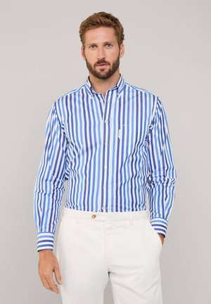 Camicia a righe blu e bianche con maniche lunghe, dotata di una piccola tasca sul petto e polsini a righe in contrasto. Vestibilità su misura.