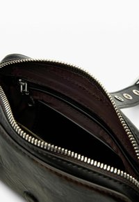 Musta nahast koti sisemus lukuga, tumeda kangakatte ja lisalukuga taskuga. Tekstureeritud välimine pind.