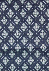 Tissu bleu marine avec un motif floral composé d'éléments vert clair et blancs, disposés en forme de losange avec de petits accents en pointillés.