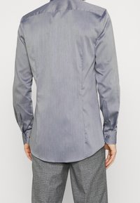 Camicia a maniche lunghe a righe grigie con colletto alla coreana con bottoni, caratterizzata da una texture sottile e polsini con occhielli arrotondati.