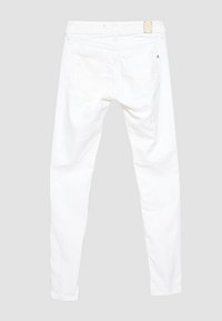 Jeans en denim blanc avec une coupe slim. Ils disposent de cinq poches, de passants pour ceinture et d'une étiquette de marque subtile sur la ceinture arrière. Texture lisse.