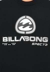 Czarny t-shirt z białym nadrukiem przedstawiającym fale oraz tekstem "BILLABONG SPEC73" wyraźnie umieszczonym na przodzie.
