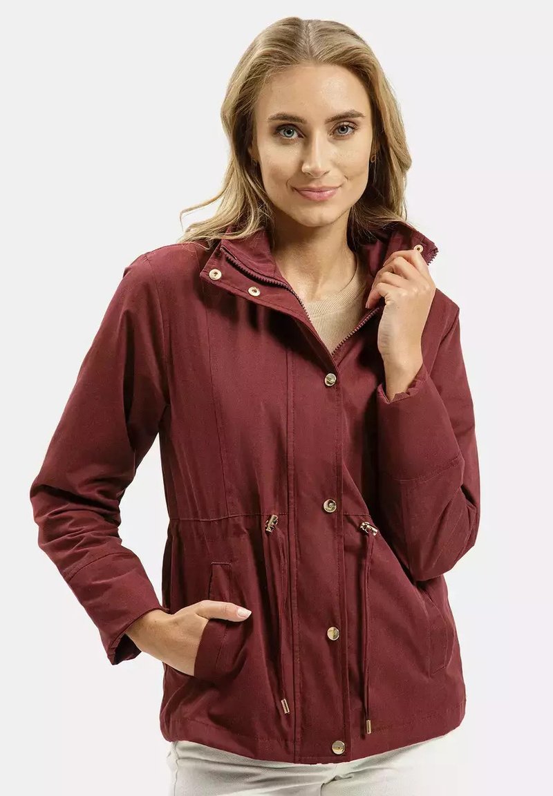 Bordowa, lekka kurtka z wysokim kołnierzem, elastycznym paskiem w talii, dwoma przednimi kieszeniami i złotymi napami. Gładka tekstura, casualowy krój.