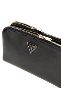 Portafoglio in pelle nera con due scomparti con zip in tonalità oro, caratterizzato da un logo triangolare in argento sul davanti per l'identificazione.