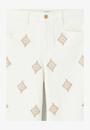 Pantalon blanc avec des motifs en losange brodés marron, espacés uniformément sur le tissu, et une fermeture boutonnée marron visible à la taille.