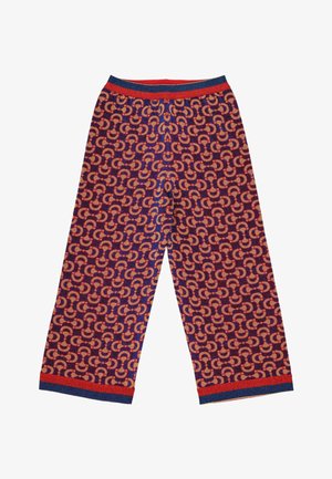 Pantalon à jambes larges avec un motif en fer à cheval rouge et bleu répétitif et une ceinture et des poignets rayés rouges et bleus sur fond blanc.