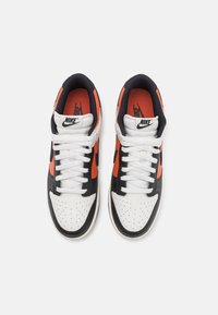 Sneakers Nike con tomaia in pelle nera, bianca e arancione, dotate di punta perforata, colletto imbottito e lacci piatti bianchi.