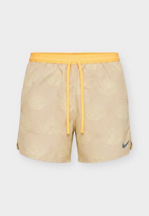 Μπεζ αθλητικό σορτς με ελαφρύ πουά μοτίβο, κίτρινη ελαστική μέση με κορδόνι και μικρό γκρι λογότυπο Nike στο αριστερό πόδι.