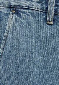 Modra jeans tkanina z teksturiranim tkanjem, z rumenimi šivi in zgornjim gumbom. Material je trpežen in tesno tkano.