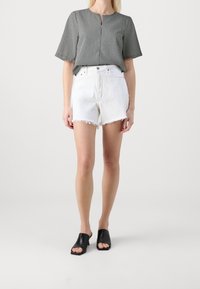 Svart och vit rutmönstrad kortärmad topp med nyckelhålsringning, kombinerad med vita fransade denimshorts och svarta öppna klackskor.