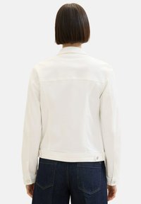 White denim jacket with a collar, back yoke, and side buttons; features long sleeves and a fitted design with a smooth texture.