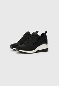 Black sneakers with suede and leather upper, featuring a white midsole and silver accent on the heel; laced design with prominent branding.