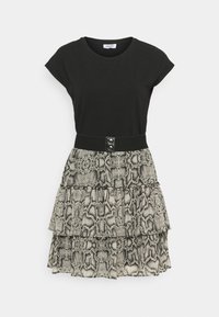 Schwarzes T-Shirt mit kurzen Ärmeln, kombiniert mit einem schichtenartigen Schlangenprint-Rock in Grautönen und Beige, der einen schwarzen Taillenbund mit Knöpfen hat.