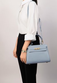Borsa a tracolla in pelle azzurro chiaro con un design strutturato, manico superiore, finiture dorate e una tracolla rimovibile. Presenta una superficie testurizzata e una chiusura a scatto.