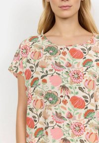 Blusenshirt mit kurzen Ärmeln in Creme, das lebendige Blumen in Pink, Grün und Orange zeigt, mit einem runden Halsausschnitt und einem lockeren Schnitt.