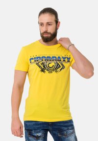 Yellow cotton t-shirt with printed graphics featuring "CIPOGBAXX" in blue and black, round neck, short sleeves, and a relaxed fit.