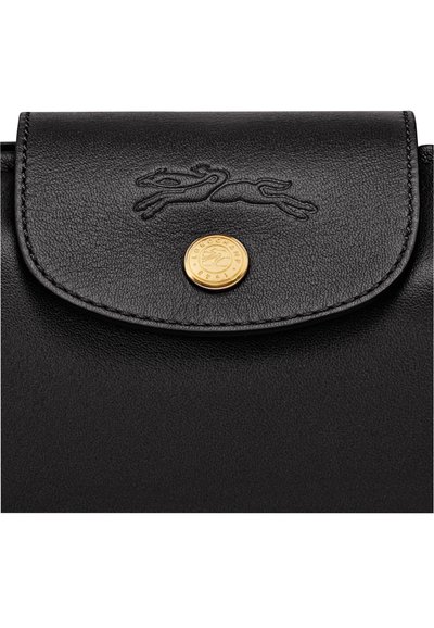 Black leather bag flap with embossed running horse logo and round gold button engraved with brand name and year.