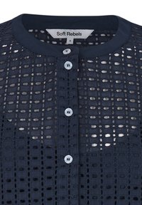 Blouse en dentelle bleu marine avec col rond, devant boutonné, et étiquette "Soft Rebels" taille petite à l'intérieur du col.